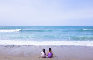 Sea shore with two small girls facing the sea