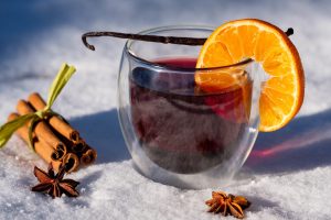 A glass of mulled wine with an orange in the snow.